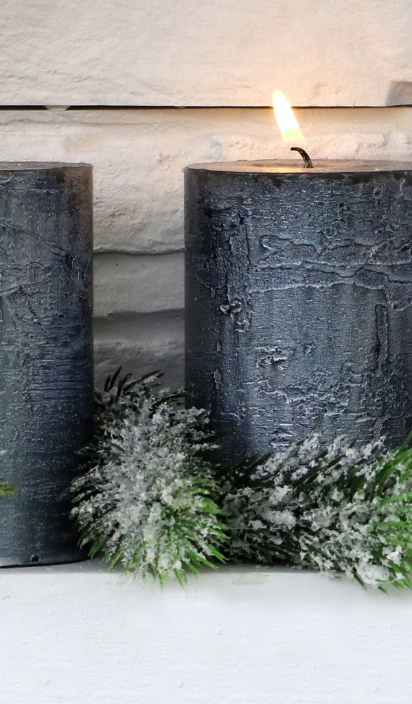 Две большие зажженные свечи у стены