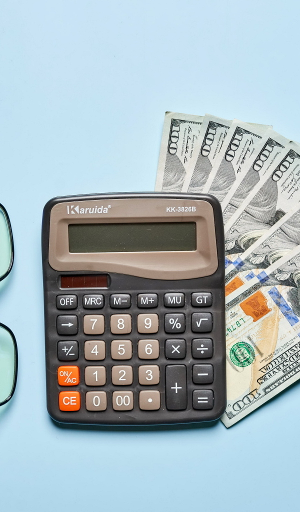 Калькулятор, очки и доллары на голубом фоне