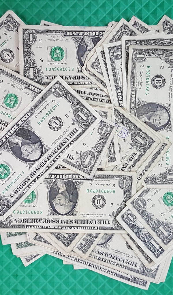 Много купюр в один доллар на зеленой поверхности