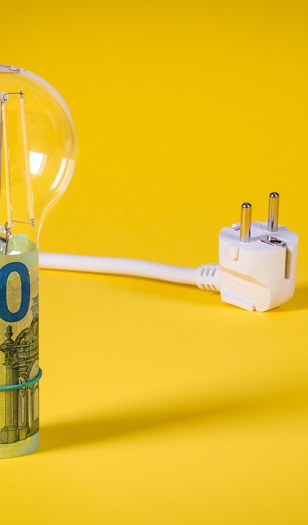 Лампочка с деньгами и розеткой на желтом фоне