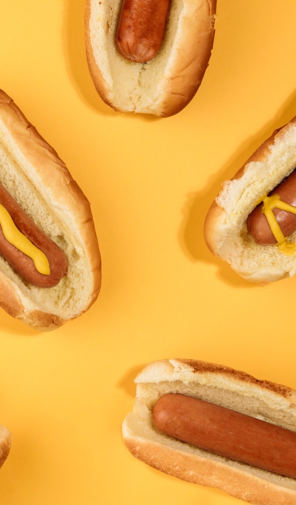 Аппетитные хот доги на желтом столе