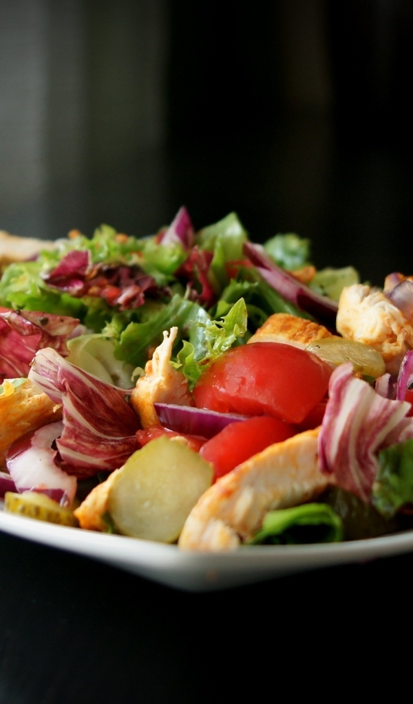 Аппетитный салат в белой тарелке на черном фоне