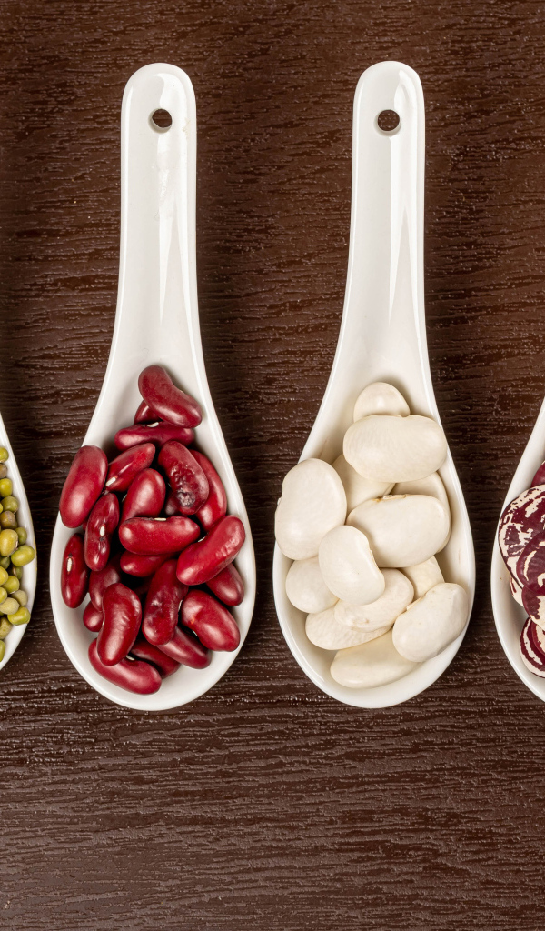 Бобовые зерна в белых ложках на столе