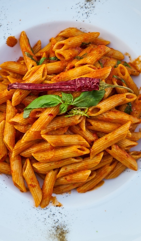 Вареные макароны на большой тарелке с красным перцем