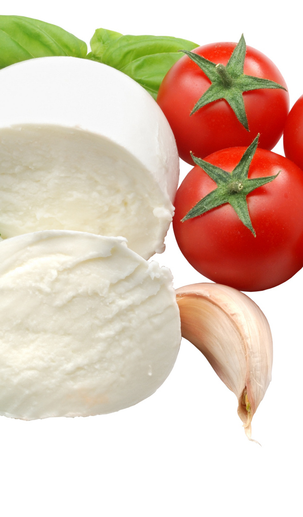Сыр на белом фоне с помидорами, листьями базилика и чесноком