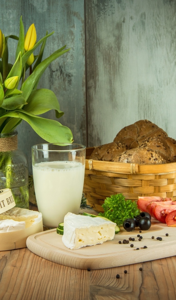 Сыр с овощами на столе с хлебом и букетом тюльпанов