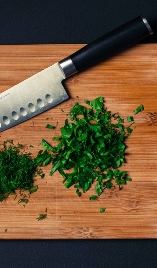Нарезанная зелень на доске с ножом