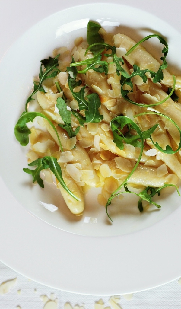 Блюдо с листьями рукколы в большой белой тарелке