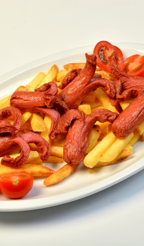 Картофель фри на тарелке с помидорами и сосисками