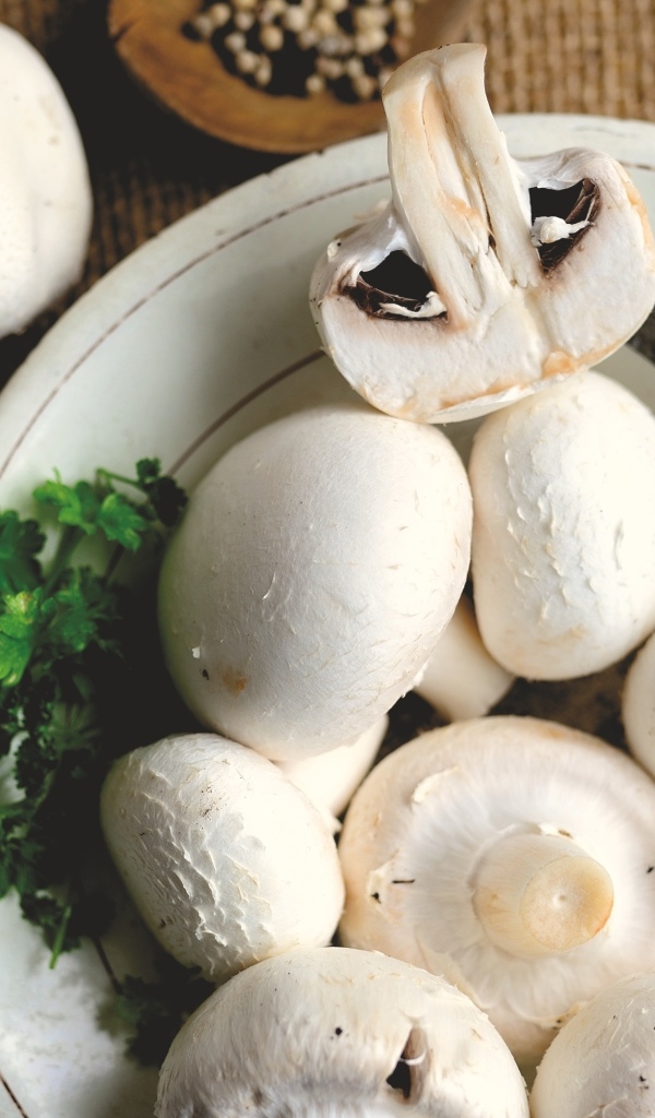 Свежие шампиньоны на тарелке на столе