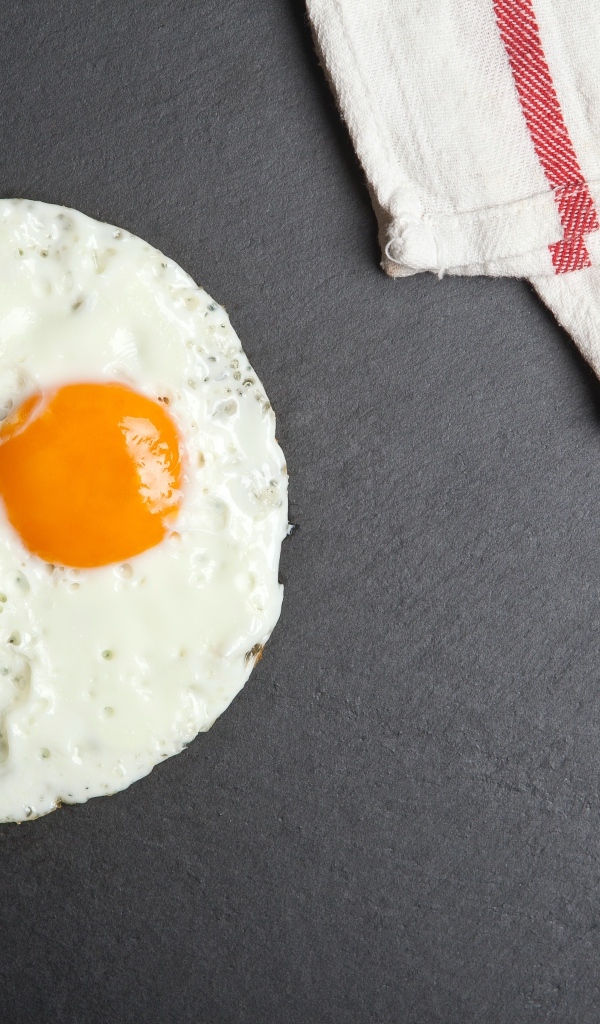 Яичница глазунья на сером столе с полотенцем