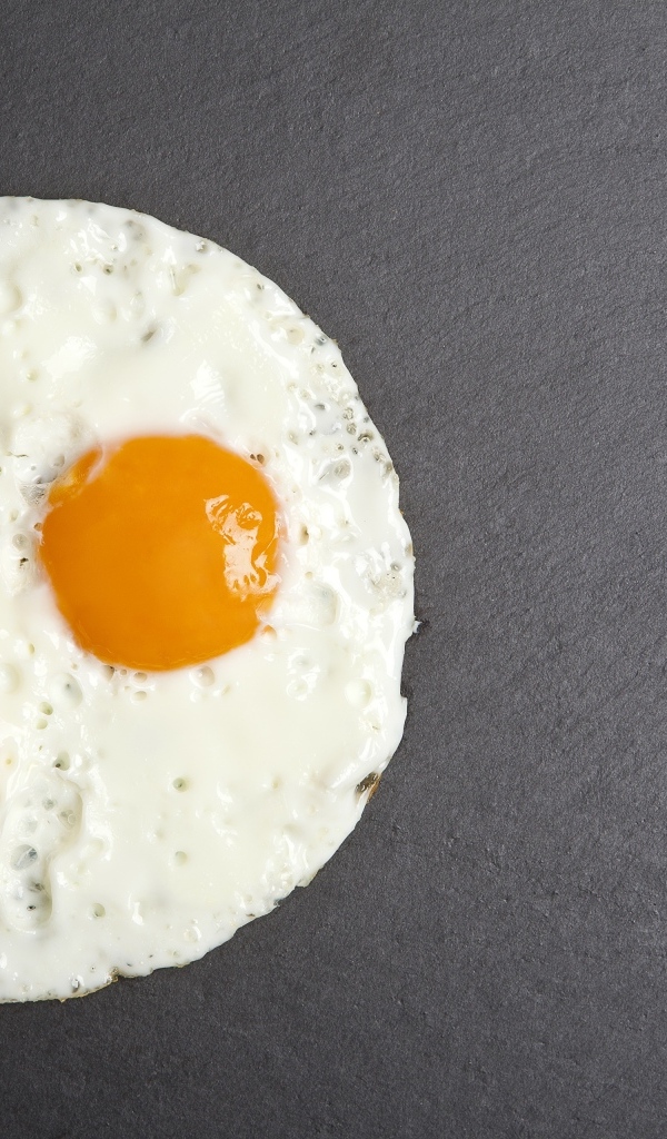 Яичница глазунья с вилкой на сером столе