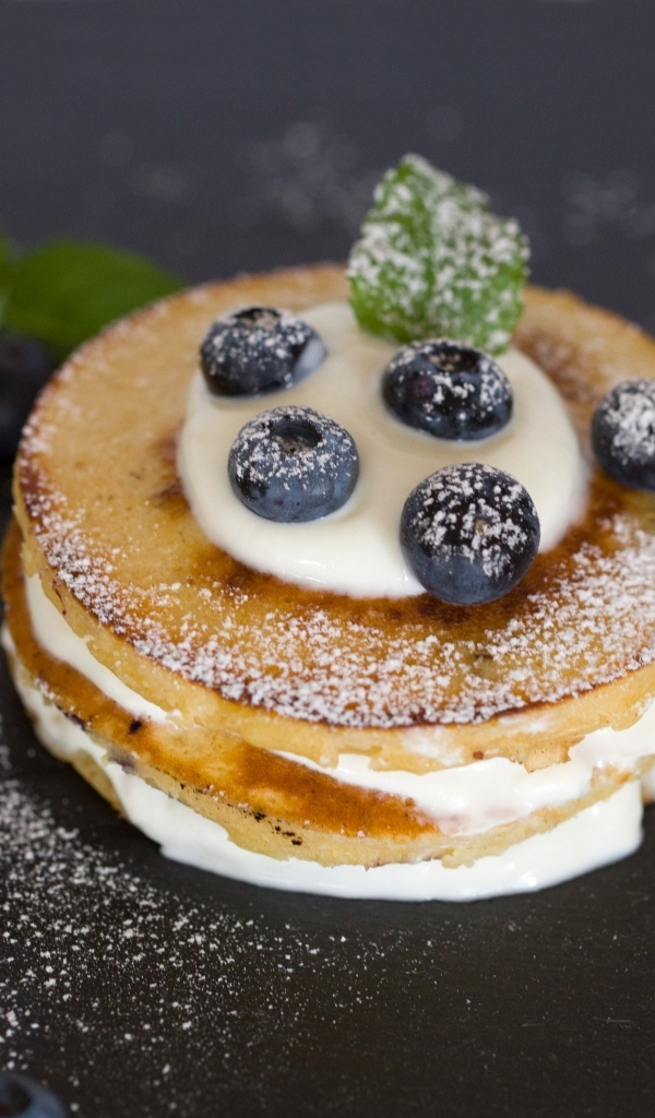 Оладьи с кремом и ягодами черники на столе