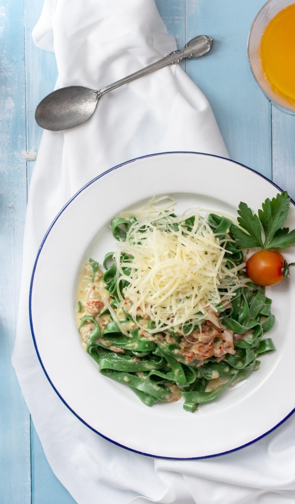 Зеленая лапша с сыром на столе с хлебом и зеленью