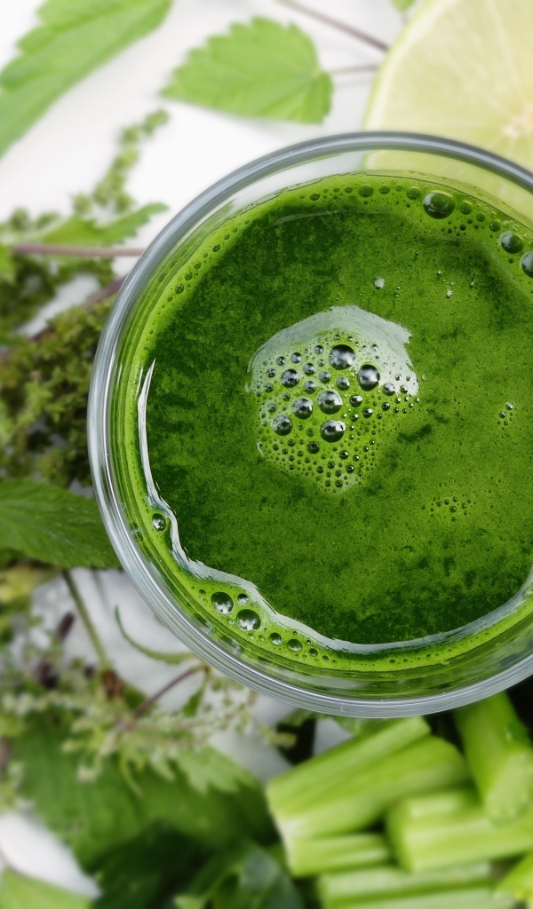 Зеленый овощной смузи в стакане на столе