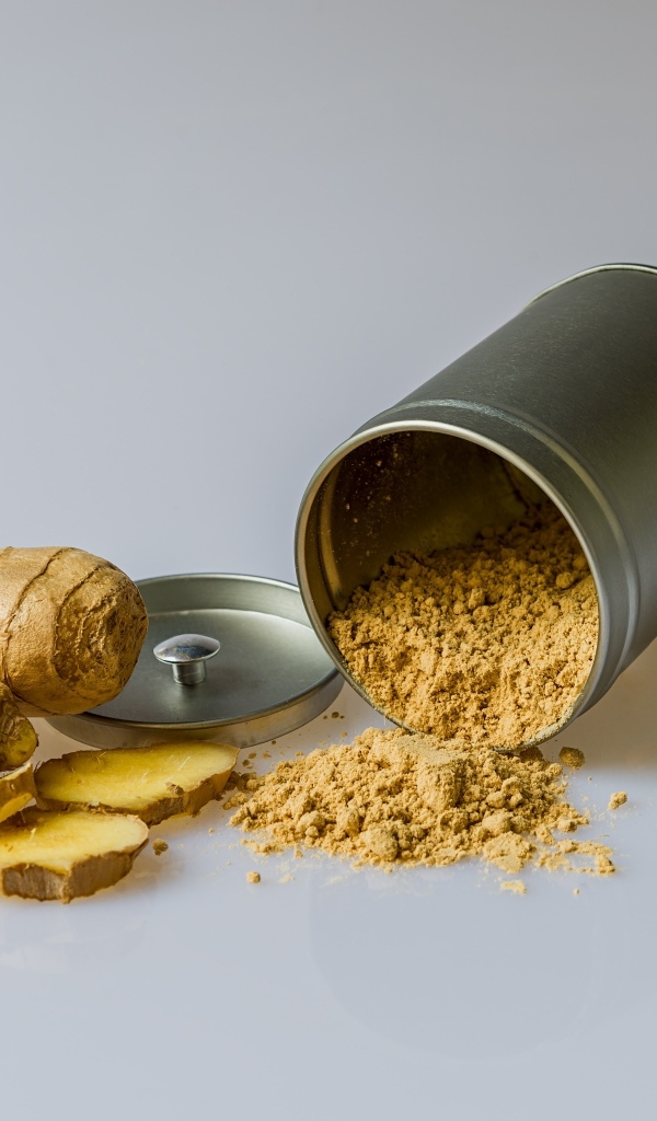 Молотый имбирь с корнем на сером фоне