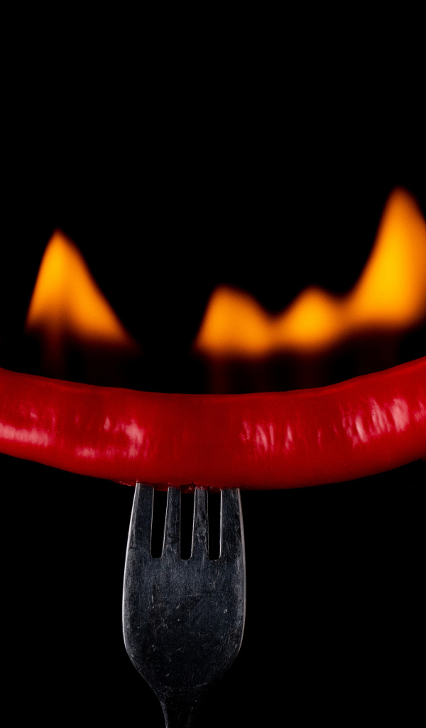 Жгучий красный перец на вилке на черном фоне