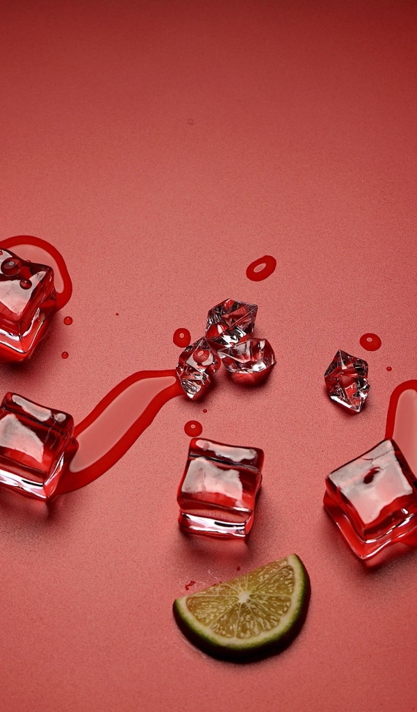 Кубики льда на красном фоне с кусочком лайма и стаканом