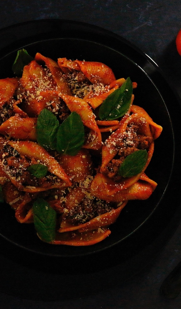 Большие макароны с фаршем в черной тарелке