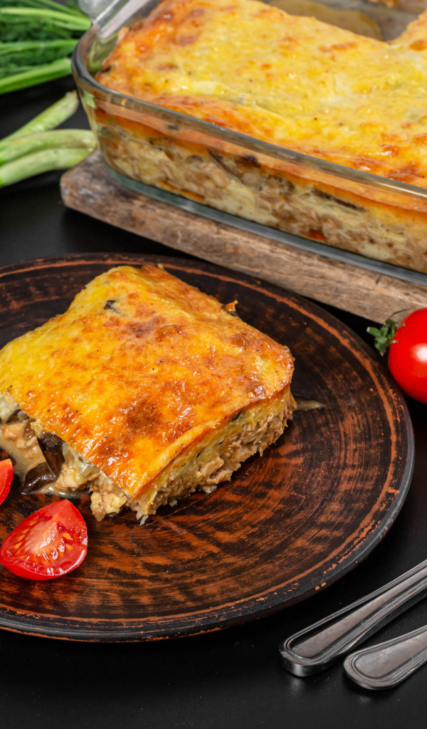 Лазанья на тарелке с помидорами и зеленью