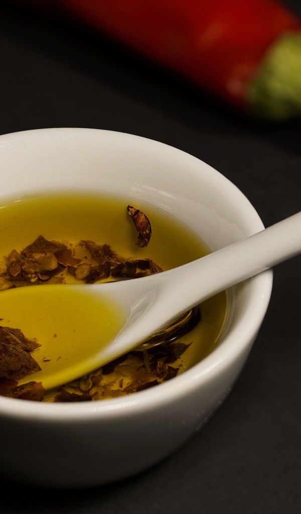 Оливковое масло в тарелке на столе с перцем и чесноком