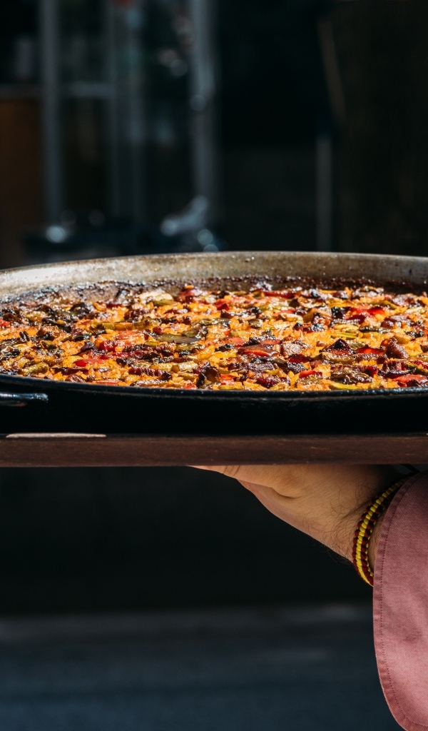 Блюдо паэлья в руках 