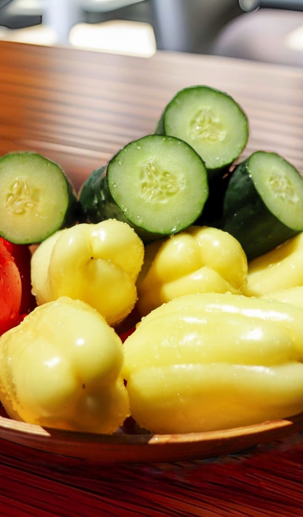 Перец, помидоры и зеленые огурцы на тарелке на столе