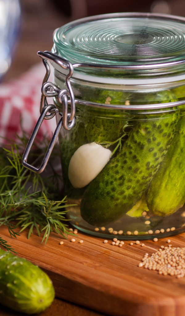 Маринованные огурцы в банке на столе со свежими