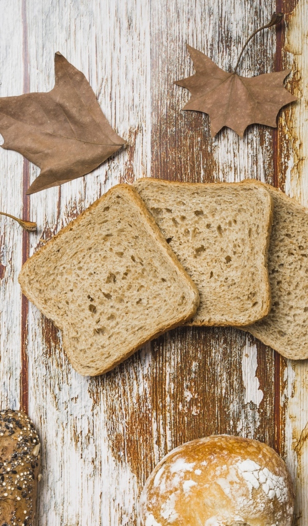 Куски хлеба с листьями на деревянном столе