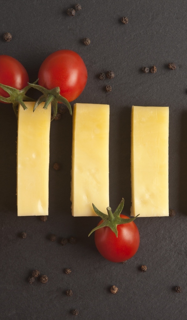 Кусочки сыра с помидорами на сером столе