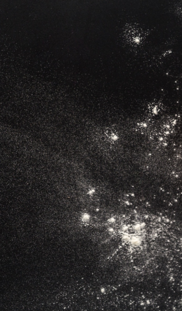 Сырое тесто на черном столе с мукой