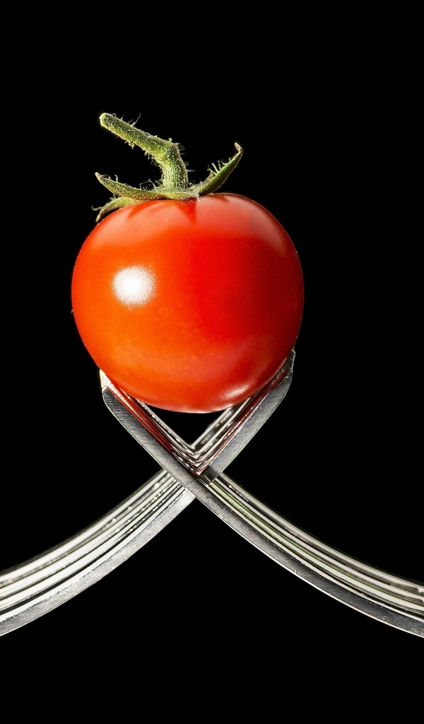 Красный помидор с вилками на черном фоне