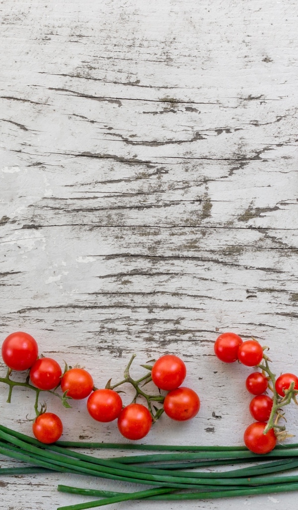 Красные помидоры с зеленым луком на деревянном столе