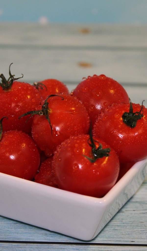 Красные мокрые помидоры в белой тарелке