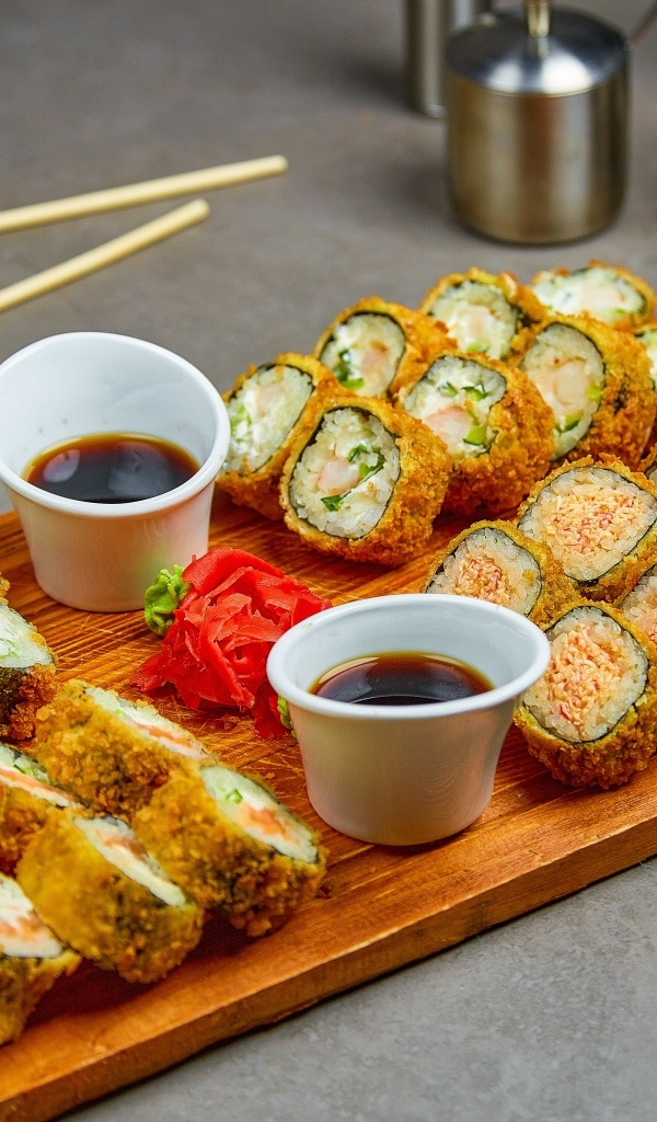 Роллы с соевым соусом на доске на столе