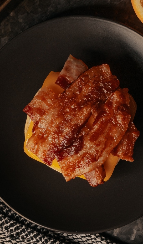 Бутерброд с сыром и жареным беконом на тарелке