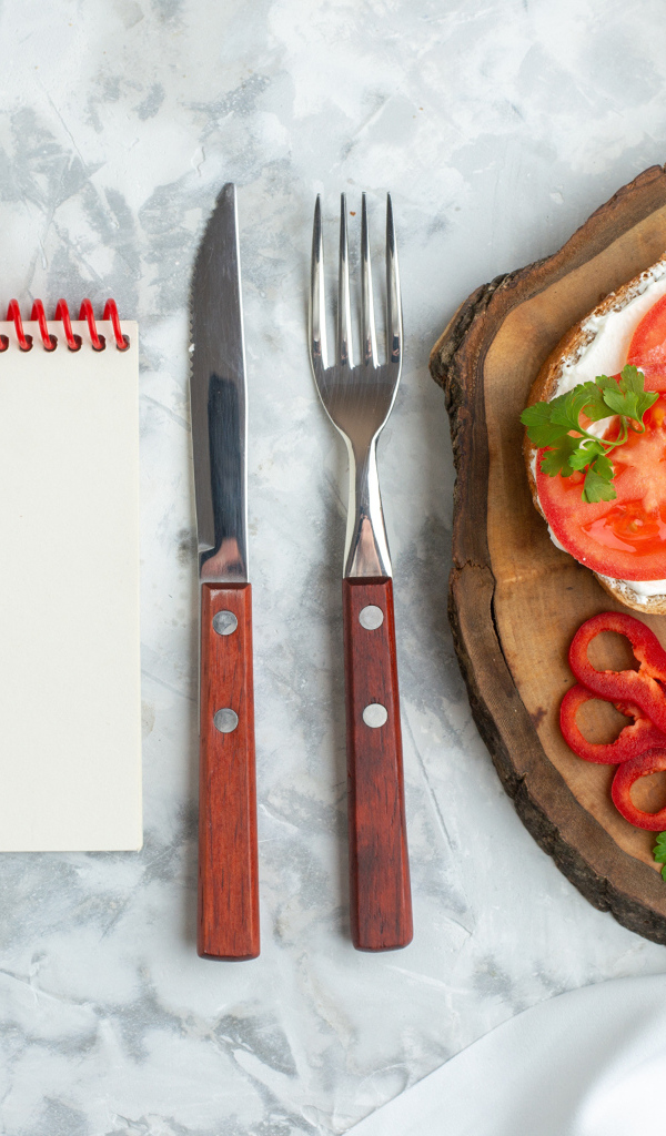 Бутерброды на столе со столовыми приборами и блокнотом