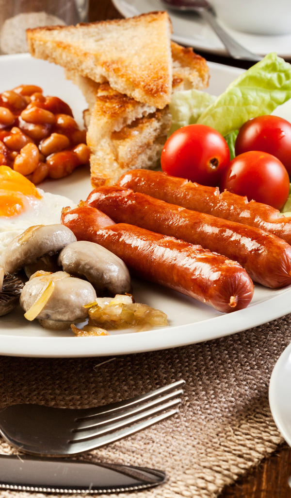 Яичница, сосиски и овощи на тарелке на завтрак