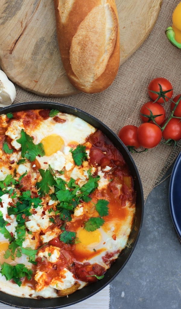 Яичница на столе с овощами и батоном