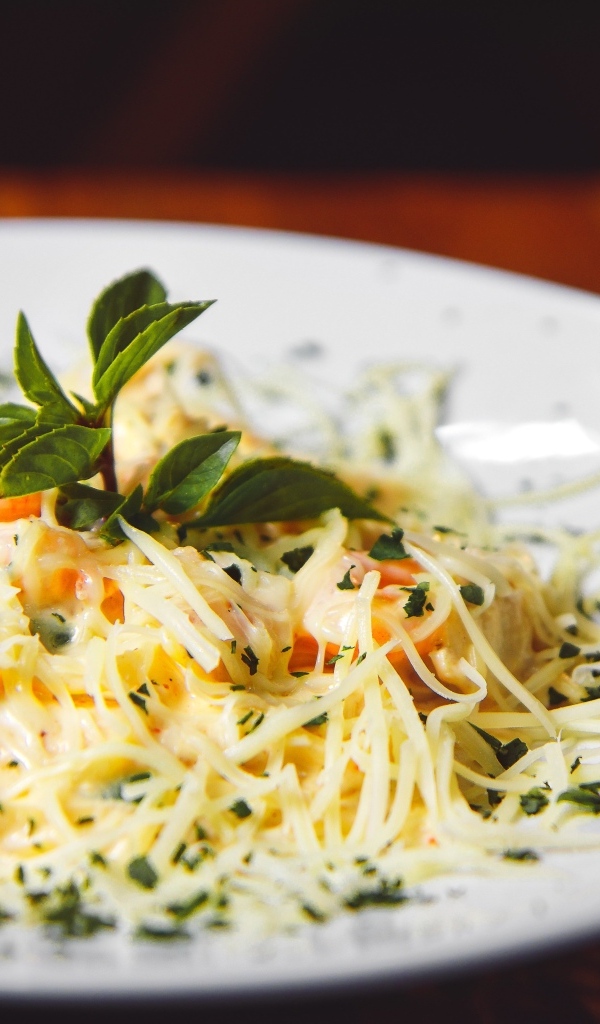 Спагетти с сыром и помидорами на белой тарелке