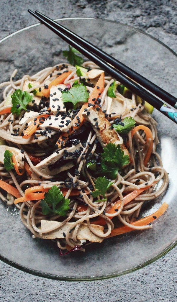 Спагетти с мясом и овощами в тарелке с китайскими палочками