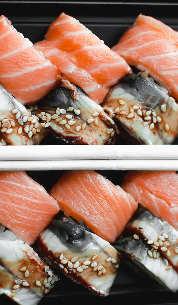 Суши с рыбой на черной тарелке с палочками