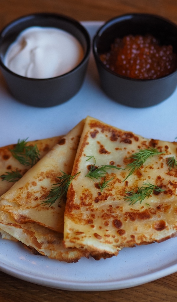 Тонкие блинчики на тарелке с красной икрой и сметаной