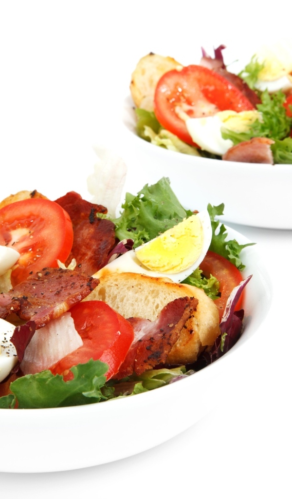 Две миски вкусного салата на белом фоне