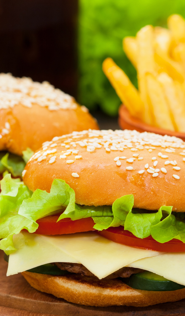 Два больших гамбургера на столе с картофелем фри