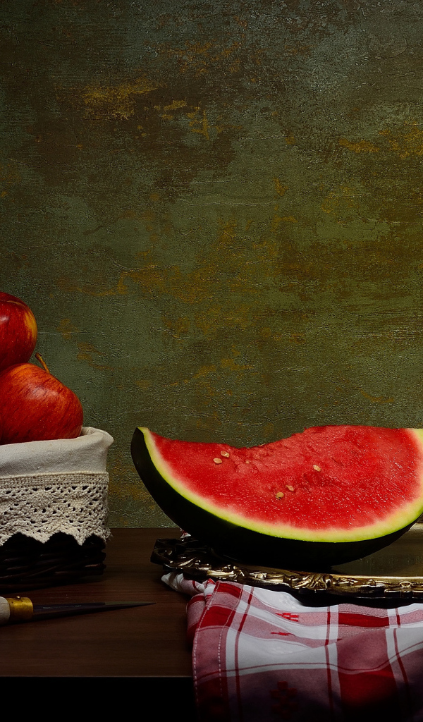 Скибки арбуза на столе с яблоками 