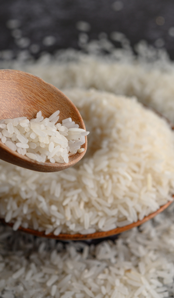 Белый рис на столе с деревянной ложкой 