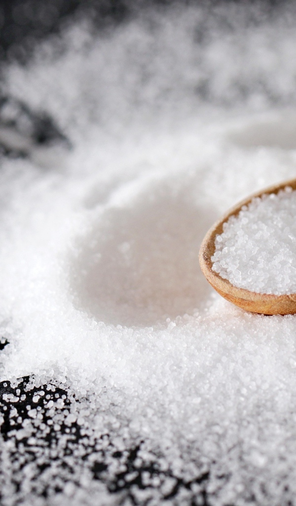 Деревянная ложка с солью на черном столе