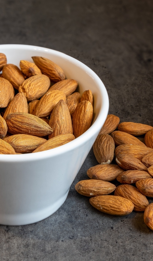 Миндальные орехи в белой пиале на столе