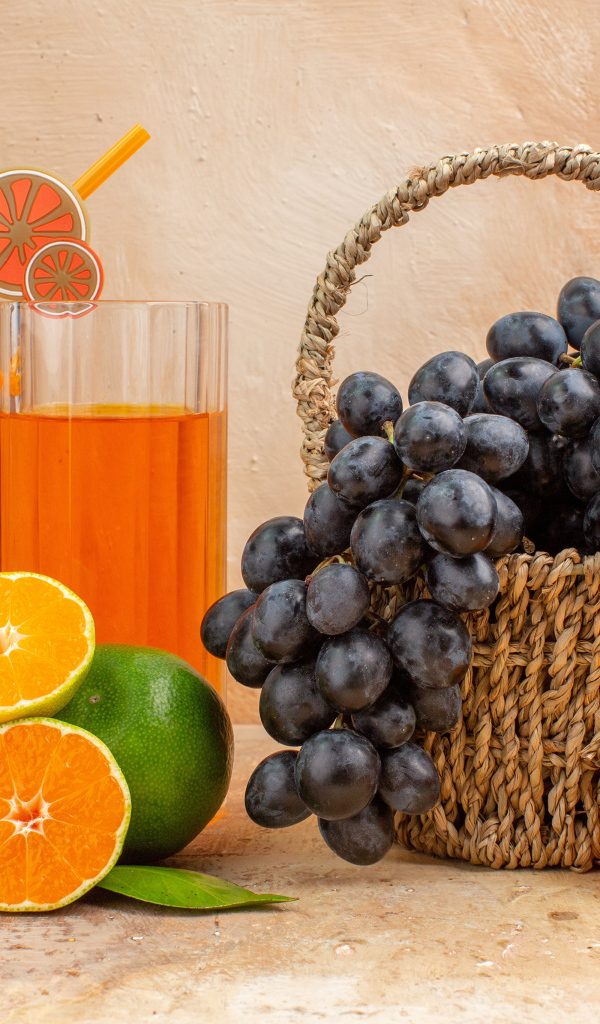 Корзина с виноградом на столе с апельсинами и лаймом